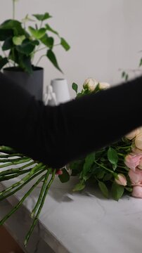 Florist forms a bouquet on the table from pink bush rose Christie