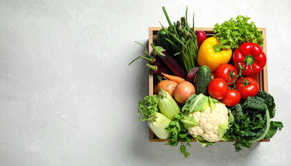 Fresh vegetables in wooden crate with tomatoes, cauliflower, lettuce, bell pepper, and asparagus on light background, healthy and colorful food concept