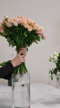Florist puts a bouquet of pink bush roses in a vase