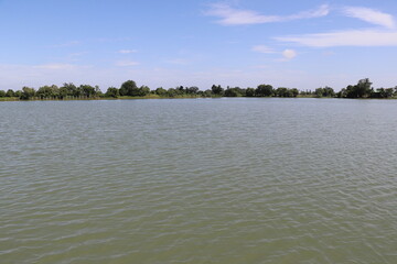 Peaceful lake surface reflecting blue sky under calm sunny day