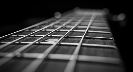 Close up of a black and white electric guitar fretboard with strings