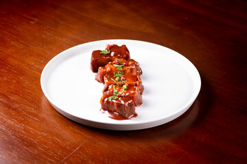 plate of sliced ​​pancetta gourmet meat served with sauce and spices on wooden table at angle