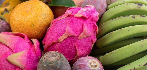Vibrant tropical fruits close-up. Papaya, dragon fruit, mango, green bananas, prickly pear, lime, lemon and orange. Exotic healthy diet ingredients rich in vitamins and antioxidants. © Olha