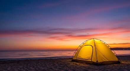 Illuminated tent on beach at sunset with vibrant sky and calm ocean