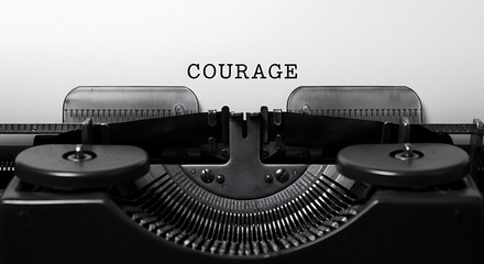 COURAGE typed on vintage typewriter paper, close-up. Monochrome message of strength, bravery, and determination.