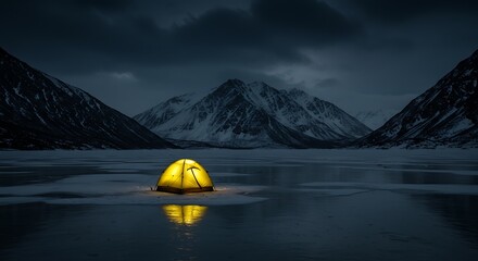 Illuminated tent on frozen lake with mountain range under a dark sky