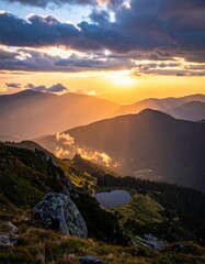 Mountain sunset with golden light illuminating valleys and a small lake
