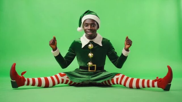 Elf sitting on green background wearing green outfit with red and white striped leggings and shoes christmas elves green screen video