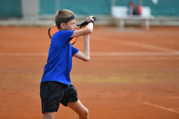 Young boy playing tennis on real court outdoor