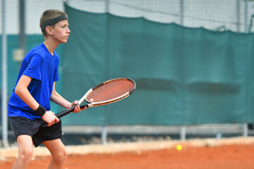Young boy playing tennis on real court outdoor