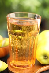 Delicious cider in glass and apples on table outdoors, closeup