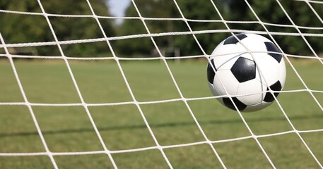 Hitting soccer ball in net outdoors, closeup. Football game