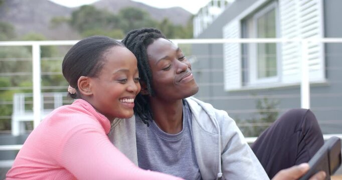 African American couple extending tablet for balcony selfie capturing moments and reviewing images