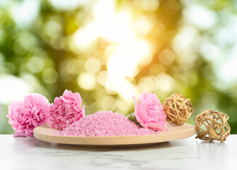 Pink sea salt and flowers on white marble table outdoors