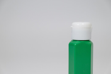 Small green plastic bottle with white cap on plain background