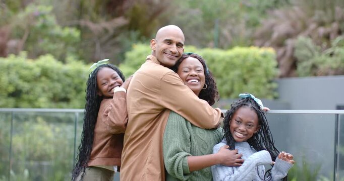 Diverse family stepping onto backyard deck hugging close for portrait as camera zooming on smiles