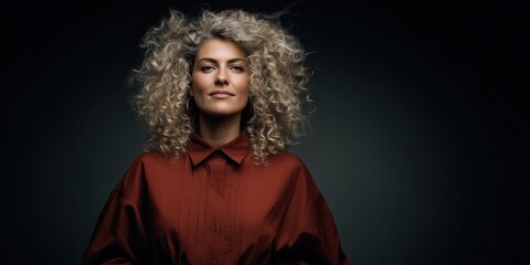 Confident Woman with Curly Hair in Stylish Outfit Against Dark Background
