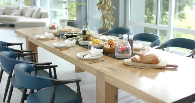 At beginning camera is panning along dining table revealing loaf, plates and showcasing lounge area