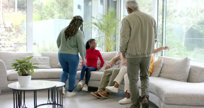 Diverse family greeting visiting relatives walking into living room on sectional sofa for portrait