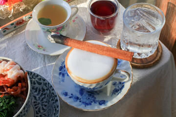 Hot cappuccino with burn cinnamon stick.  Cozy autumn warm coffee beverage with spice herb. 