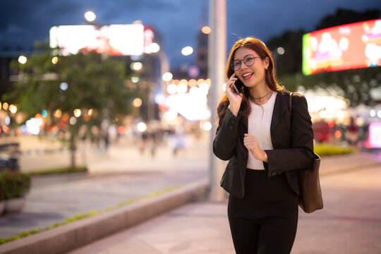Asian businesswoman walking city street talking on phone
