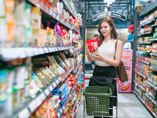 Woman choosing groceries in supermarket aisle shopping