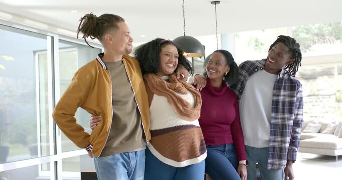 Four friends entering living area through sliding glass doors linking arms and cheering under lamp