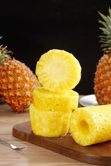 Fresh Golden Pineapple Slices on Wooden Board with Whole Tropical Fruits