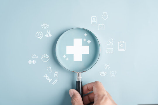 Medical health care insurance concept with hand holding magnifying glass and health icons, protection, screening, diagnosis, treatment, wellness, and preventive healthcare.