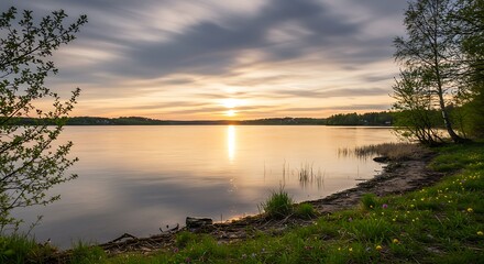 Serene sunset over calm lake with trees and reflective water