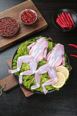 Raw Frog Legs with Chili Peppers and Spices - Exotic Culinary Ingredients on Dark Wooden Background