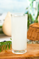 Fresh Coconut Milk Glass with Whole Coconut on Wooden Table - Tropical Healthy Drink