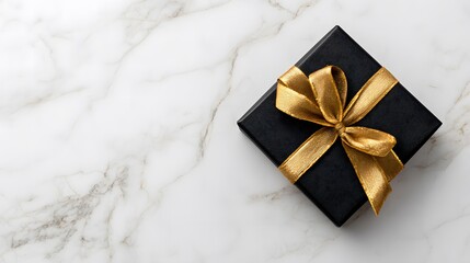 A black gift box with a golden ribbon and bow on a white marble background