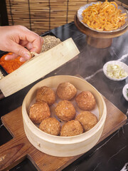 Asian Steamed Meatballs in Bamboo Steamer with Traditional Side Dishes and Noodles