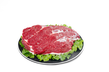 Fresh Raw Beef Brisket Cut on Black Plate with Lettuce Garnish