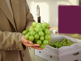 Fresh Green Seedless Grapes in Hand with Box in Modern Kitchen - Healthy Eating Concept