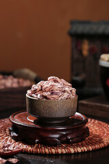 Colorful dried tea leaves in small ceramic bowl on wooden tray - traditional Asian tea ceremony ingredients