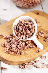 Colorful Pinto Beans in White Spoon on Wooden Board - Healthy Legumes and Grains