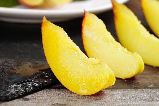 Fresh Sliced Nectarine Wedges with Yellow Flesh and Red Skin on Wooden Board
