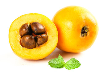 Fresh Yunnan Mountain Loquat Fruit Cut in Half with Seeds and Mint Leaves on White Background