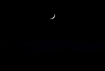 Silvery crescent moon hangs low over a dark, rolling landscape,  dark sky,  nature