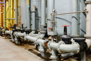 Industrial plumbing setup with valves and pipes in a facility under bright lights