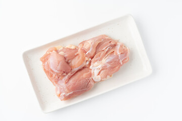 白背景にお皿に載せた生の鶏もも肉
