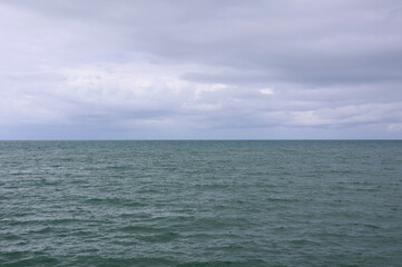Obraz premium Vast calm ocean water under a cloudy overcast sky
