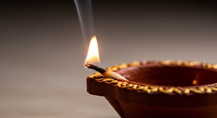 Lit diya with a flame and smoke brown terracotta pot and golden detailing