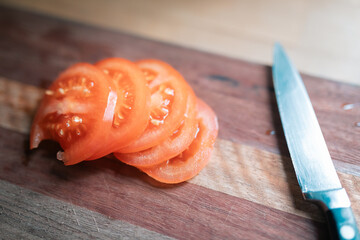 Sliced tomato on chopping board in kitchen with sharp knife