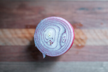 Top down view of red onion on wooden chopping board