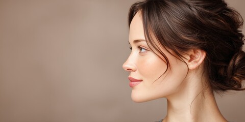 Fototapeta premium Elegant Profile Portrait of a Woman with Soft Makeup and Natural Hair in a Neutral Background