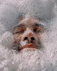 Close-up of a person's face submerged in soapy bubbles, creating a unique and abstract visual