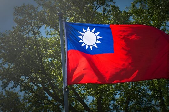 Majestic Taiwanese flag proudly waving against a vibrant blue sky amidst lush green trees, symbolizing national pride and freedom.